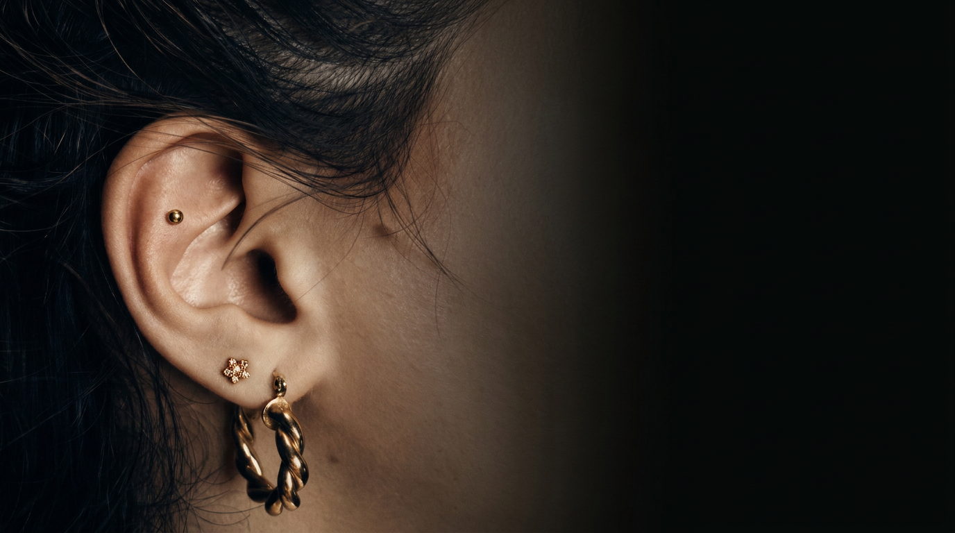 Ohr mit Helix-Stud, Lobe-Piercing und goldenem Creolen-Schmuck